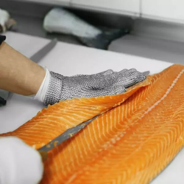 Main qui l�ve un filet de saumon avec gant cotte de maille